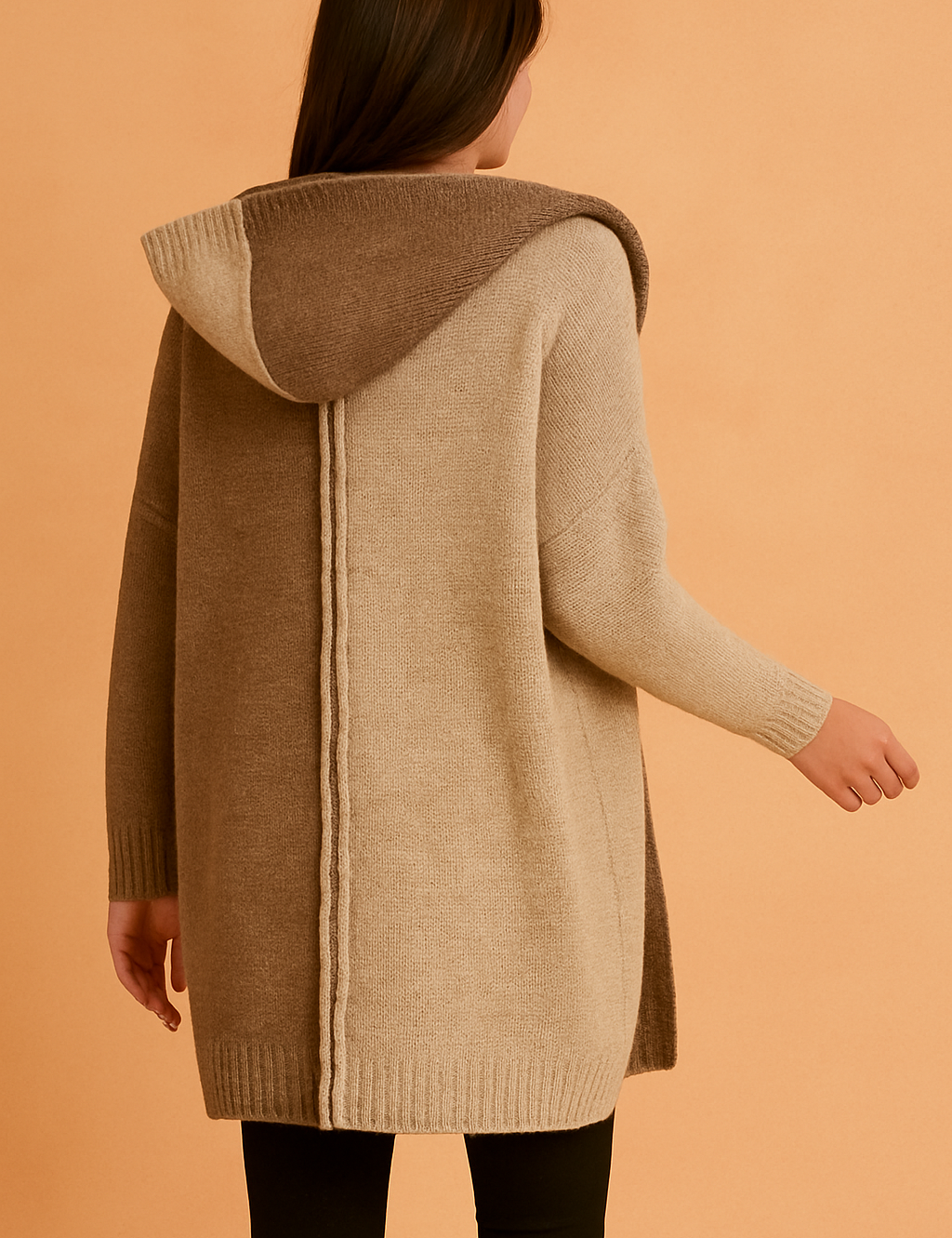 Back view of a two-tone knit hooded cardigan in light beige and medium brown, featuring a vertical seam detail, paired with black leggings.