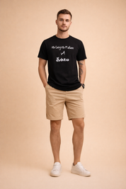 Beige cotton chino shorts with a smooth matte finish and straight hem paired with a black short-sleeve graphic t-shirt featuring crisp white typography and symbol print, styled with clean low-profile neutral sneakers for a modern casual look