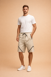 Beige performance drawstring shorts with black zipper pockets and diagonal contrast piping, paired with a clean white short-sleeve crew-neck T-shirt and minimalist white low-top sneakers for a modern casual athletic look