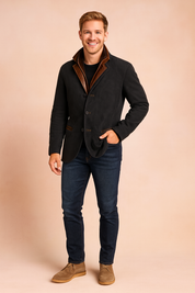 Men’s black blazer jacket with brown leather collar and trim accents, button-down front, and tailored pockets, styled with dark jeans and beige suede desert boots.
