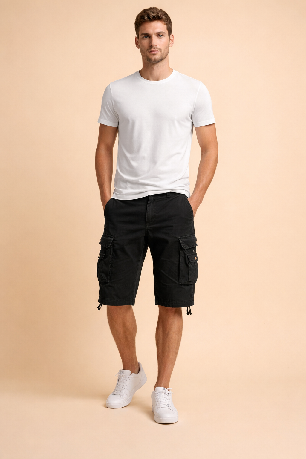 Black cotton cargo shorts with flap pockets and button details, styled with a clean white short-sleeve crew neck t-shirt and white low-top sneakers, showcasing a structured casual summer outfit with a matte fabric finish and precise stitching.