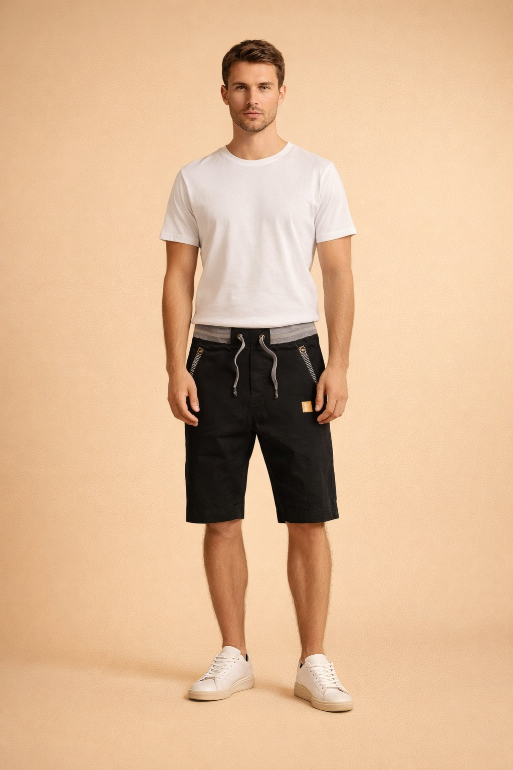 Black knee-length cotton men’s shorts with adjustable grey drawstring waistband, structured matte fabric, diagonal zip pockets with metallic detailing, subtle stitched seams, paired with a clean white short-sleeve crew-neck T-shirt in smooth cotton and minimal white low-top sneakers with a matte leather finish.