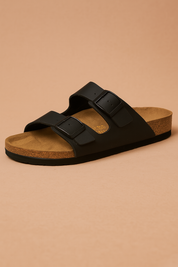  suede slip-on sandal featuring a contoured cork footbed and two wide straps with oversized brown buckles for adjustable comfort.