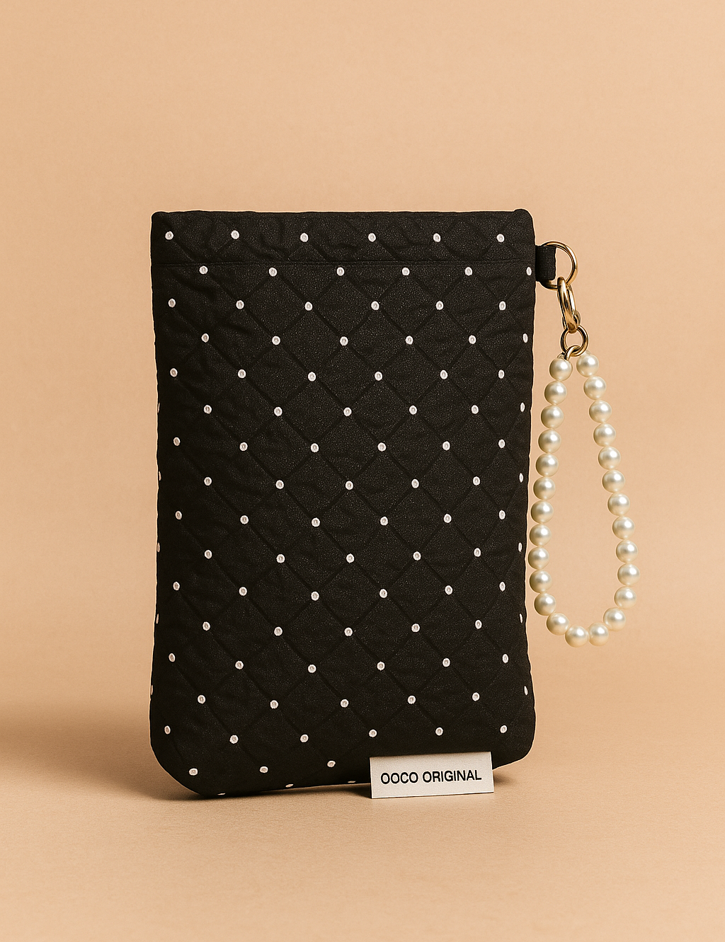 Upright black quilted pouch with delicate white pearl dots and a pearl bracelet strap, highlighted with a visible designer label and rich stitched texture.