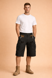 Black tactical cargo shorts with reinforced ripstop fabric, multiple utility pockets with flap and zipper closures, metal D-ring attachment, straight knee-length cut, and matte finish, paired with a solid dark navy short-sleeve crew neck t-shirt and boots