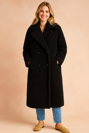 Long black teddy coat with wide lapel collar, double-breasted button closure, and full-length cut for winter wear.