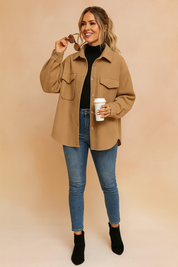 Camel beige oversized button-up jacket with flap chest pockets, relaxed fit, and long sleeves, styled with a black turtleneck, slim-fit jeans, and black ankle boots.