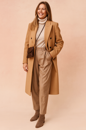 Elegant camel wool coat with double-breasted button design, paired with a beige turtleneck sweater, high-waisted pleated trousers, and taupe suede ankle boots, styled with a brown leather crossbody bag.