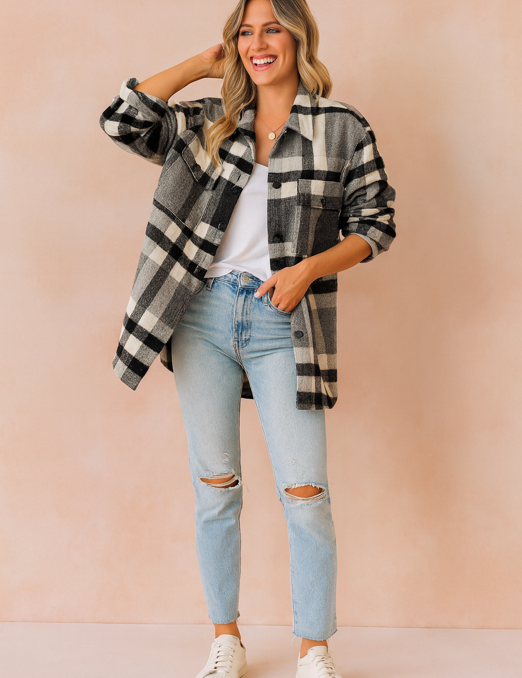 Oversized plaid button-up shacket in black, white, and gray with front flap pockets, styled over a white top, paired with light blue ripped jeans and white sneakers.