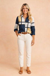 Modern color-block button-down blouse featuring navy, white, black, and metallic gold grid panels, styled with off-white high-waisted trousers, a tan belt with a gold buckle, and tan leather slide sandals for a bold, polished look.
