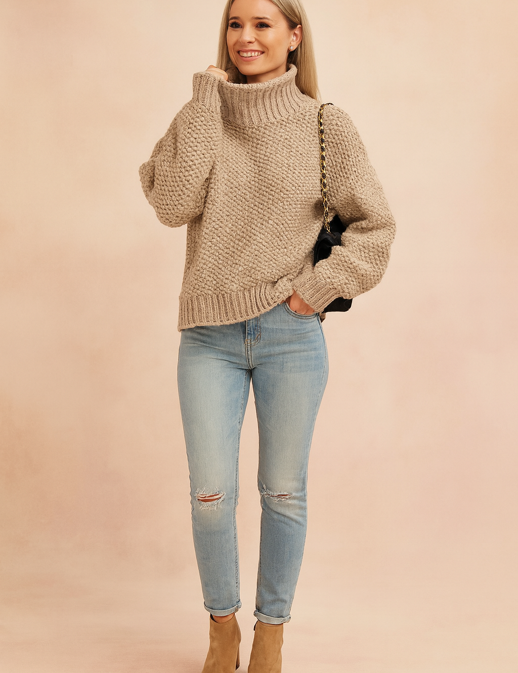 Beige chunky knit turtleneck sweater with textured pattern, paired with light blue distressed skinny jeans, tan ankle boots, and a black shoulder bag with gold chain strap.