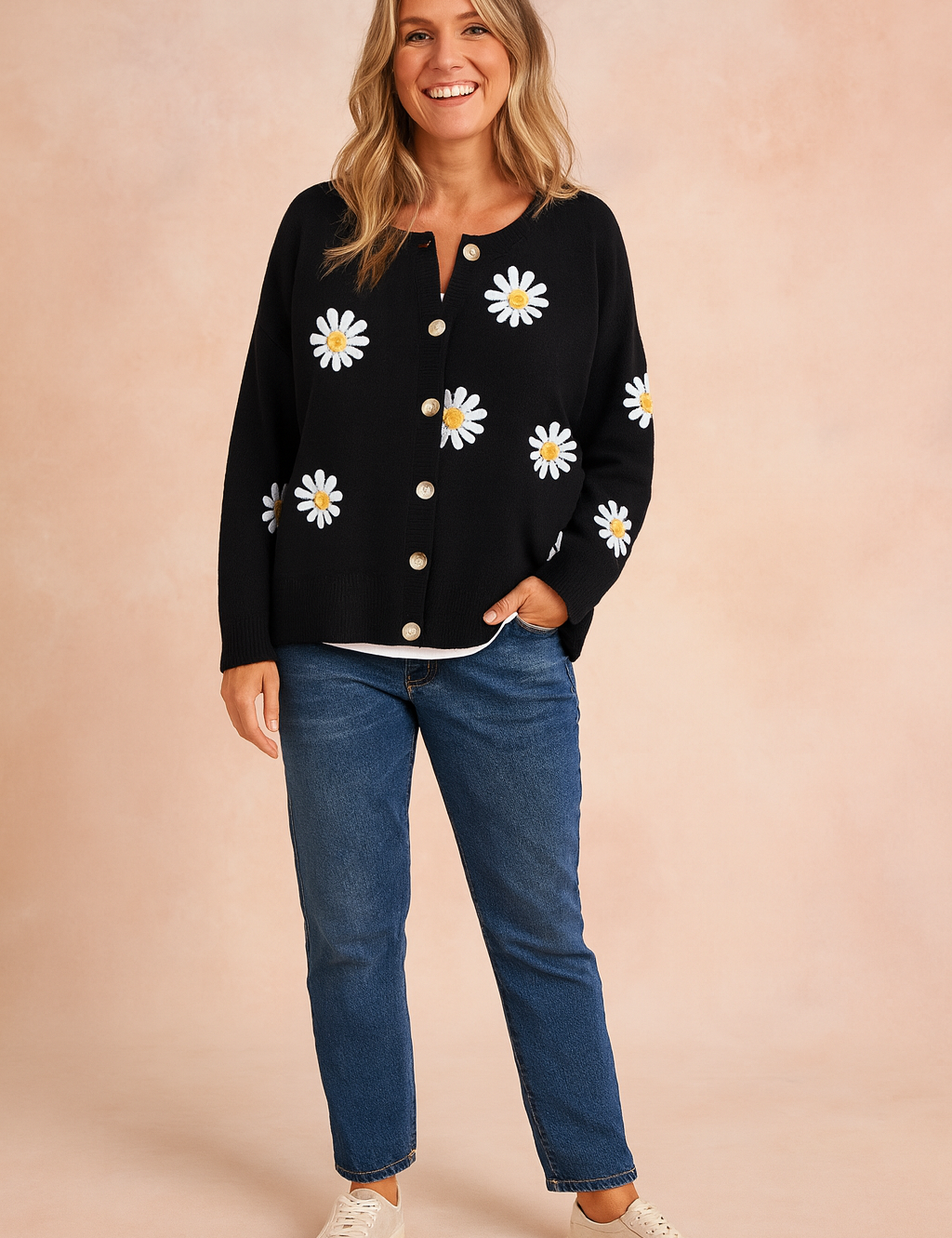 Black button-up cardigan with white daisy prints over a white inner top, paired with straight-leg blue jeans and beige sneakers.