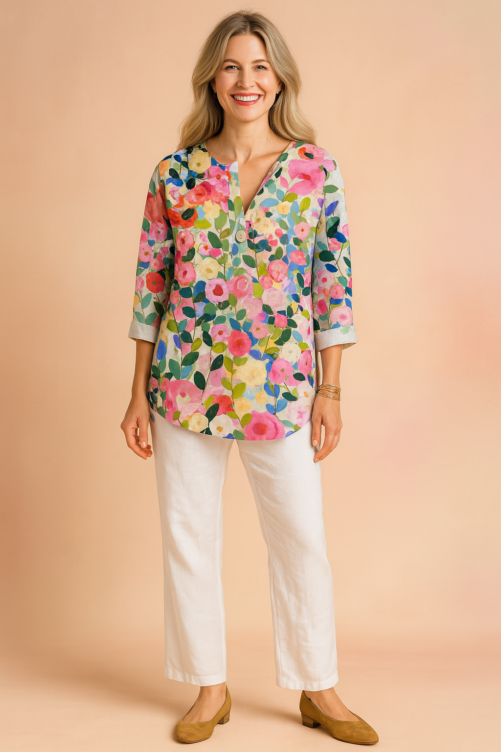 Colorful floral V-neck blouse with three-quarter sleeves, featuring a vivid multicolor garden print in pink, green, blue, and yellow tones; styled with white pants and tan block-heel shoes.
