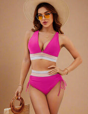 Two-piece fuchsia bikini featuring a halter-style top with plunging neckline and a wide, multicolored crochet band under the bust, paired with a high-waisted bottom that has matching crochet detailing and adjustable side ties.