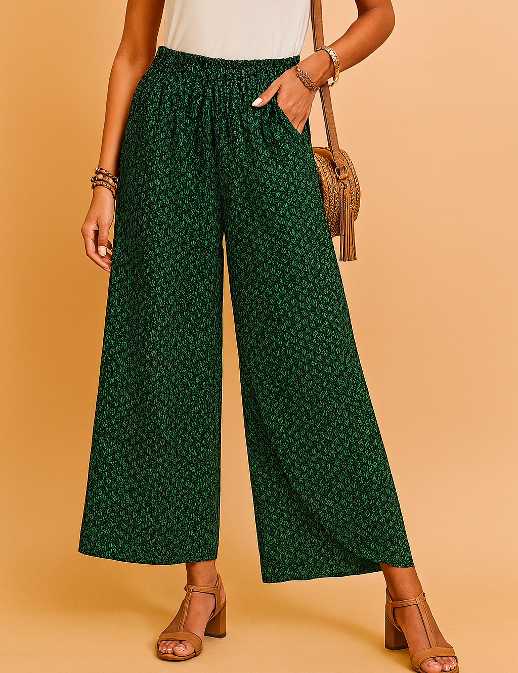 Green wide-leg high-waisted pants with a subtle black leaf print, elasticated waistband, and breezy full-length cut, styled with tan block-heeled sandals and a white tucked-in sleeveless top.