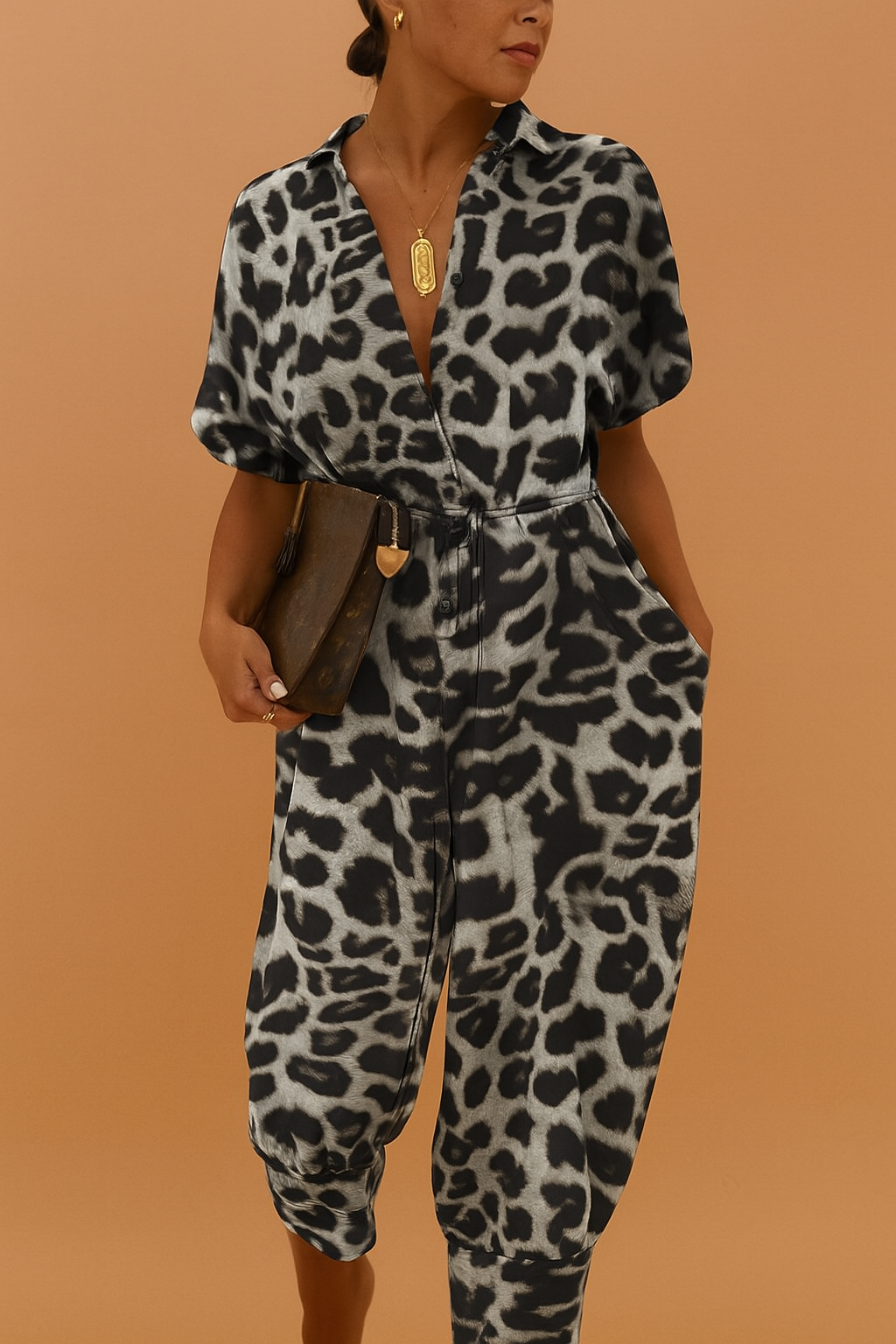 Leopard print jumpsuit with short puffed sleeves, a deep V-neckline, elastic cinched waist, and full-length tapered pants in black and gray tones.