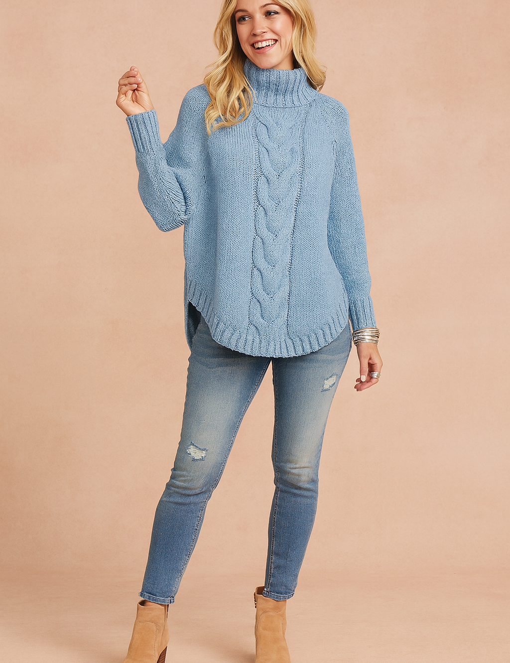 Light blue cable-knit high-neck sweater with ribbed cuffs and hem, paired with distressed light-wash skinny jeans and tan suede ankle boots.
