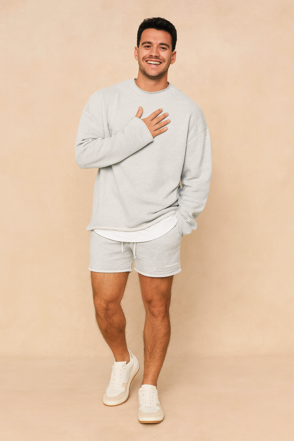 Light grey casual men’s lounge set featuring a relaxed-fit long-sleeve sweatshirt with layered hem detail and matching drawstring shorts for a minimalist streetwear look.