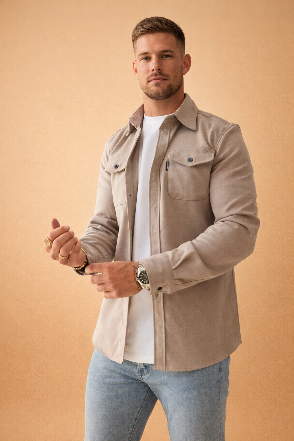 Men’s tailored beige overshirt layered over a clean white crew-neck top, paired with slim light-wash denim jeans for a refined casual look.
