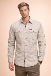 Light beige long-sleeve men’s utility button-up shirt with a structured collar, dual chest flap pockets with button closures, full front button placket, reinforced seam detailing, and a tailored straight fit.