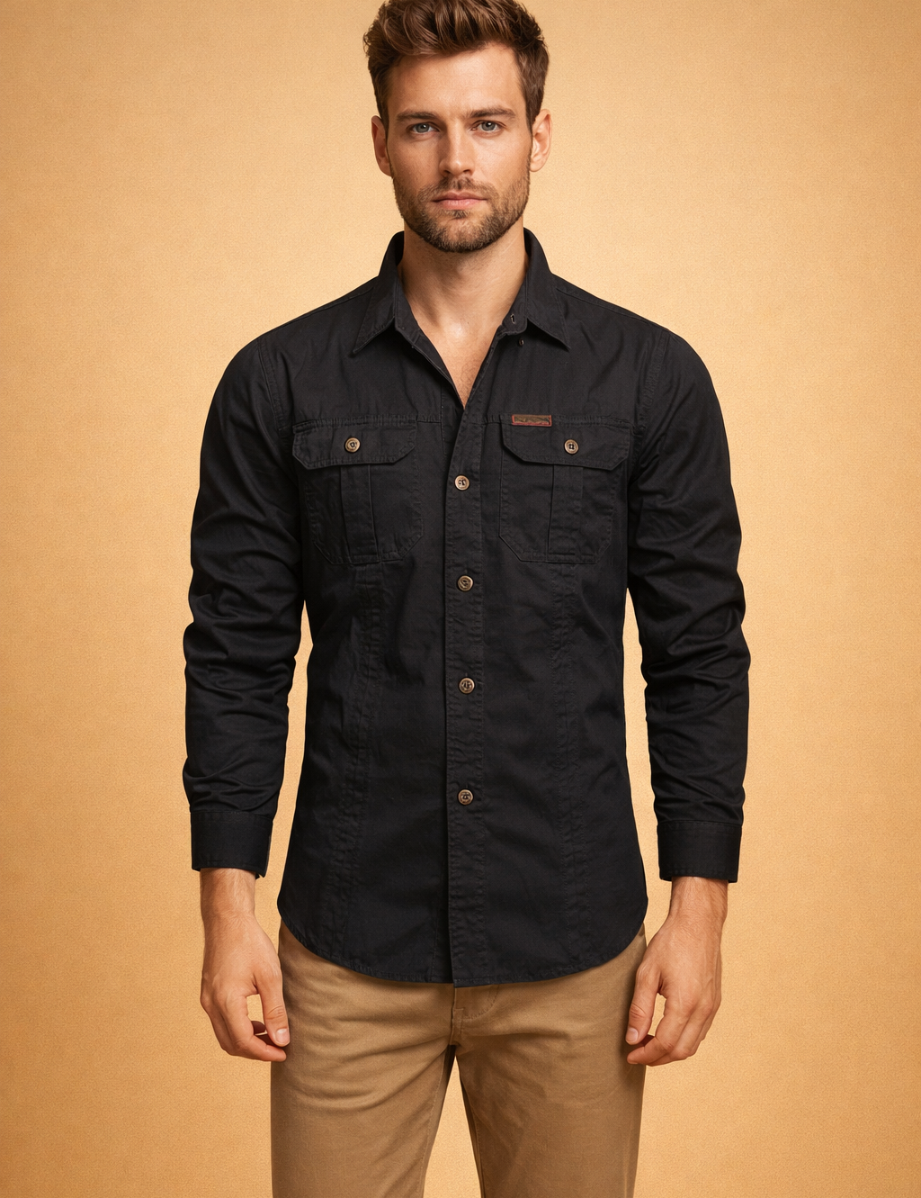 Men’s black long-sleeve button-up shirt with structured collar, front button closure, dual chest flap pockets with buttons, tailored fit, paired with straight-cut beige trousers.