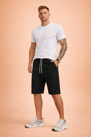 Men’s solid black casual shorts with elastic waistband and white drawstring, crafted from smooth lightweight fabric with a clean matte finish, paired with a classic heather grey short-sleeve cotton T-shirt featuring a fine jersey knit texture and neutral tone for everyday comfort.