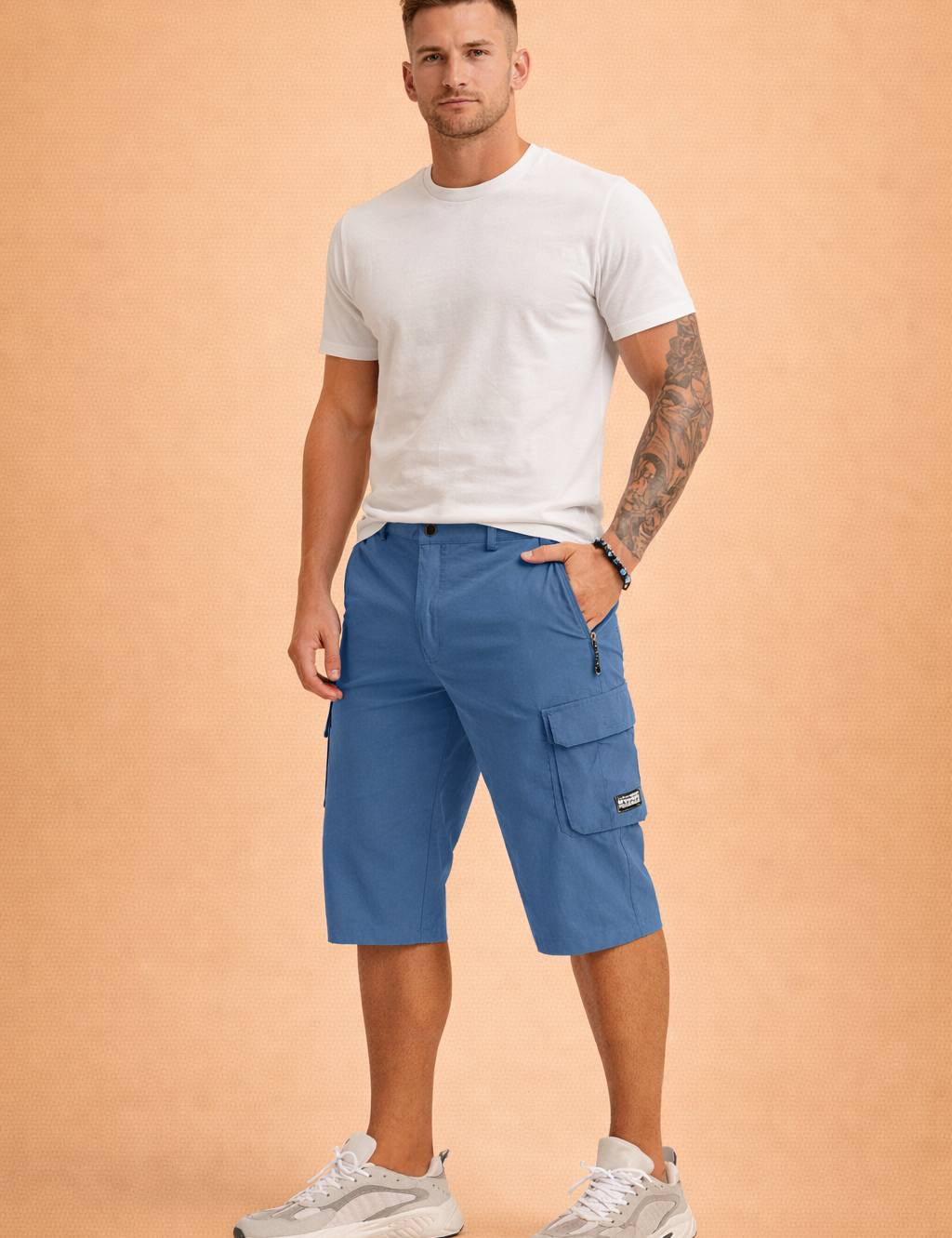 Men’s knee-length blue cargo shorts crafted from smooth woven performance fabric with a matte finish, featuring a structured waistband with single button closure, zip fly, belt loops, angled side pockets, a secure zip pocket, and a utility cargo pocket with flap and stitched logo patch, paired with a solid burgundy short-sleeve crew-neck T-shirt in soft knit fabric and white athletic sneakers with layered panels and cushioned soles.