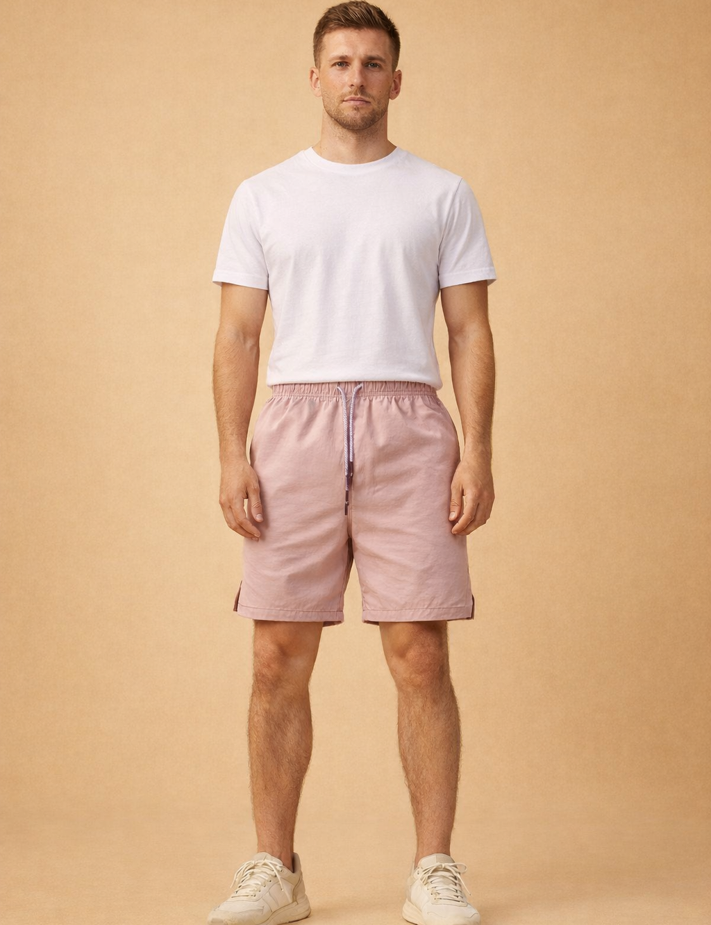 Light dusty-rose men’s summer shorts with elastic waistband and drawstring, paired with a clean neutral short-sleeve shirt and minimalist low-profile sneakers for a modern casual outfit