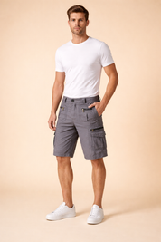Men’s grey cargo shorts with multiple zippered utility pockets and structured stitching, styled with a clean white short-sleeve t-shirt and minimalist white low-top sneakers, showcasing a modern casual summer outfit with a functional, tailored silhouette.