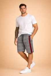 Men’s casual outfit featuring tailored knee-length shorts in a grey plaid check pattern with fine black and white lines, accented by a bold vertical red and black side stripe, elastic waistband with black drawstring, smooth woven fabric texture, paired with a solid light grey short-sleeve cotton T-shirt and clean white low-top sneakers.