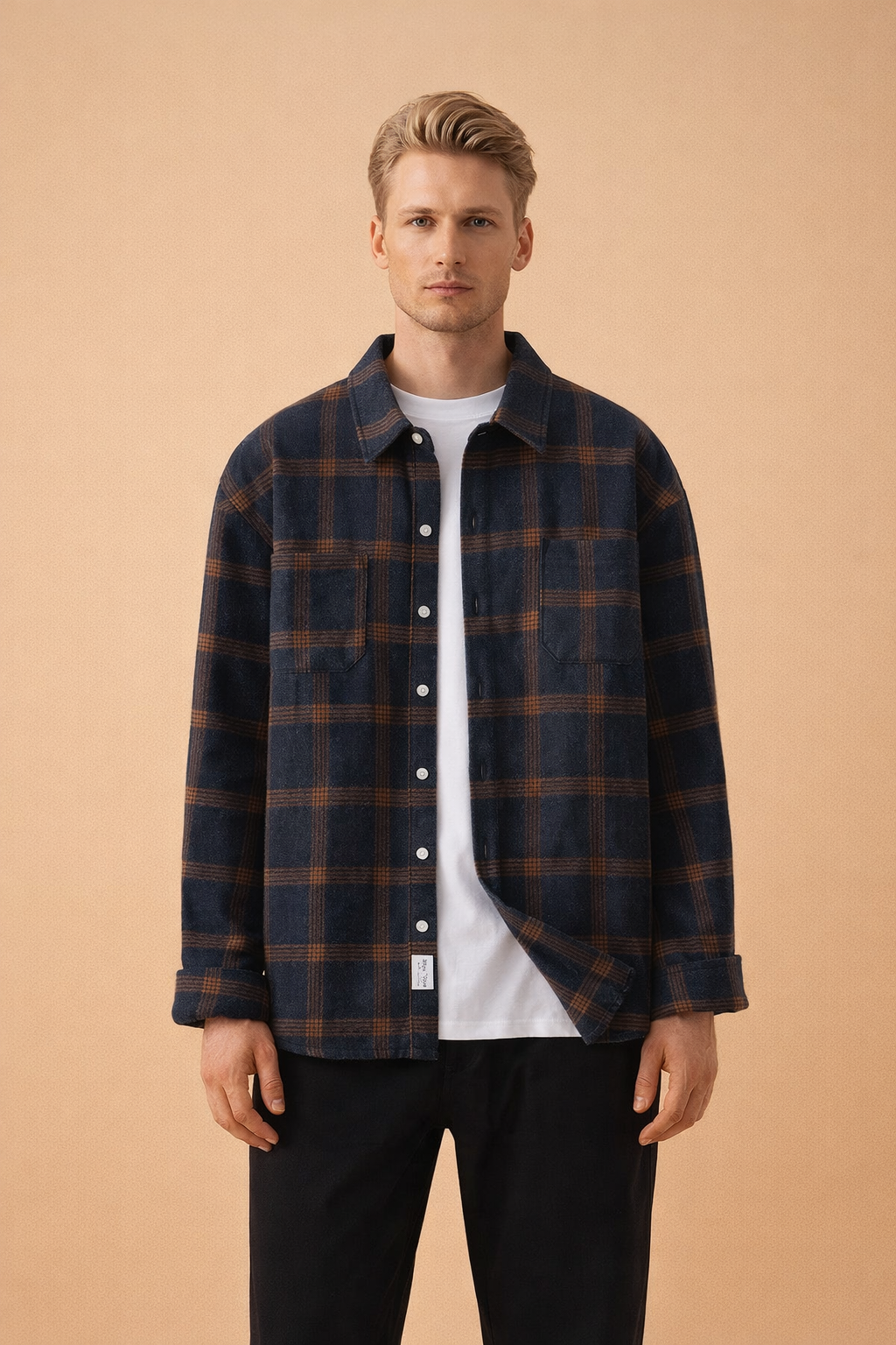 Men’s navy blue plaid overshirt with brown check pattern, long sleeves, button-front closure, chest pockets, styled open over a plain white crew-neck T-shirt and tailored black trousers