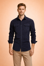 Men’s dark navy long-sleeve button-up shirt with dual chest pockets, styled with slim-fit beige trousers for a refined smart-casual outfit.