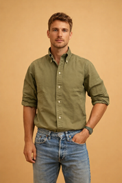 Men’s olive green long-sleeve button-down shirt with a structured collar, clean front placket, rolled cuffs, and classic blue denim jeans styled for a refined casual look.