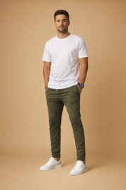 Men’s slim-fit olive jogger trousers with tapered legs and elastic waistband, styled with a plain white short-sleeve T-shirt and clean white low-top sneakers.