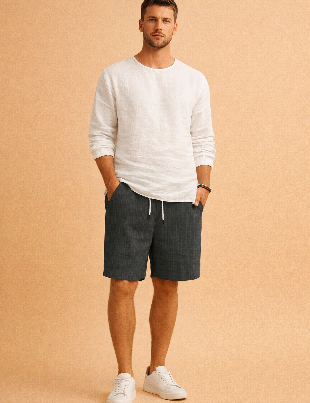 Men’s minimalist summer outfit featuring a clean long-sleeve white shirt paired with tailored ribbed drawstring shorts in a muted cool grey tone, finished with understated neutral footwear for a refined casual look.