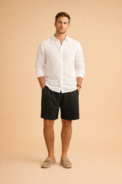 Men’s ribbed summer shorts with a clean vertical texture, tailored above-knee length, elastic waist with drawstring, styled with a crisp long-sleeve white shirt and neutral slip-on loafers for a refined casual look.