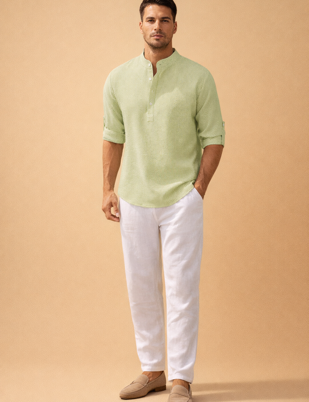Light sage green textured long-sleeve henley shirt with a fine vertical rib weave, band collar, partial button placket, and roll-tab sleeves, paired with crisp white straight-leg linen trousers and neutral beige suede loafers for a refined casual menswear look.