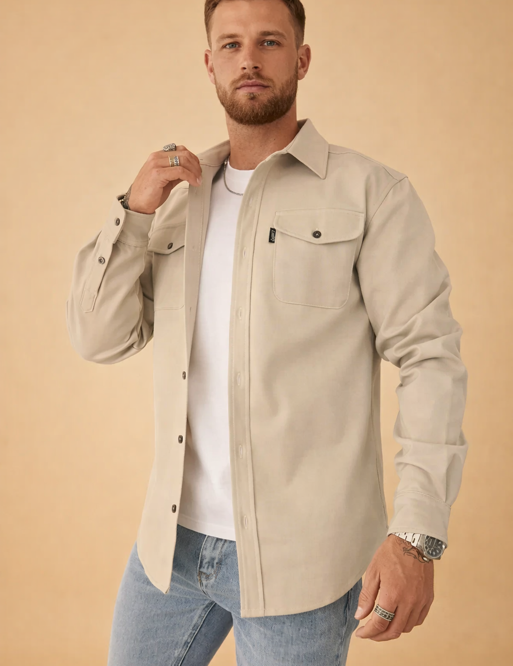 Men’s structured overshirt layered over a fitted crew-neck top, styled with straight-cut denim jeans, featuring a clean button-front design, chest flap pockets, and a tailored yet relaxed silhouette suitable for smart-casual wear.