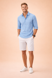 Relaxed long-sleeve button-front shirt with a casual open collar and rolled cuffs, paired with tailored knee-length shorts and clean low-profile lace-up sneakers for a refined summer smart-casual outfit.