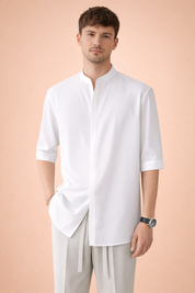 Men’s minimalist white band-collar shirt with clean concealed placket, elbow-length sleeves, straight hem, styled with light beige relaxed tailored trousers featuring a soft drape and drawstring waist.