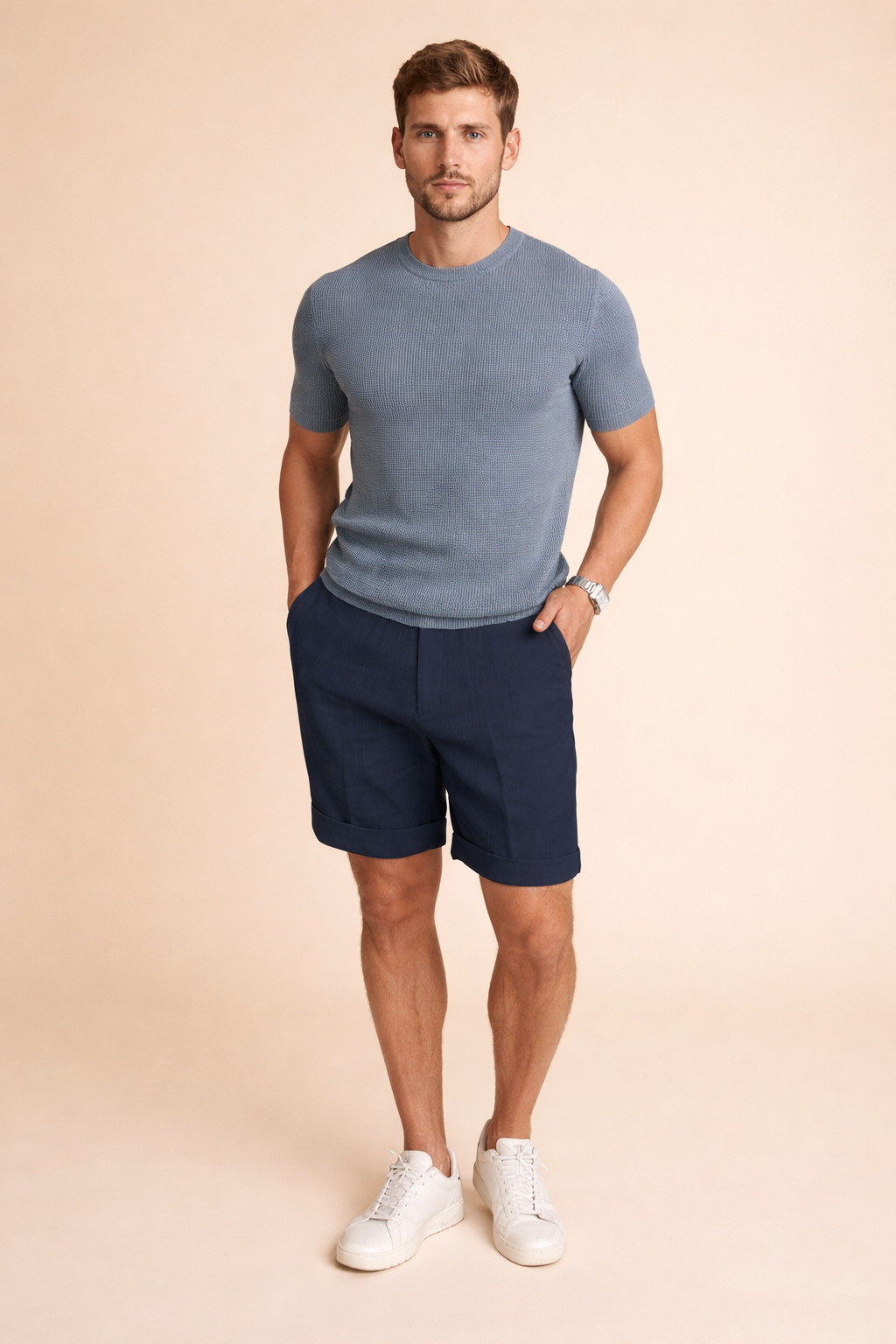 Men’s minimalist outfit featuring a smooth solid white short-sleeve T-shirt paired with tailored navy blue shorts, crafted in a clean matte fabric with a structured yet relaxed fit, finished with light grey athletic sneakers for a modern casual look.