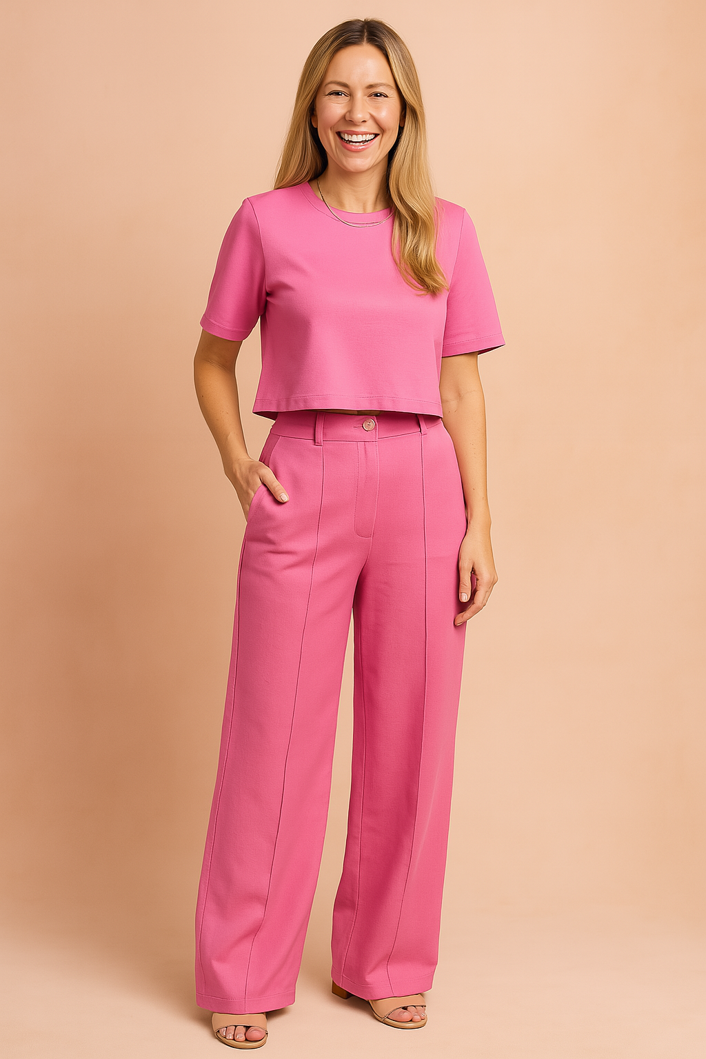 Two-piece women's coord set featuring a short-sleeve crop top and high-waisted wide-leg trousers in a solid fuchsia tone, styled with a central crease line and button-closure waistband for a sleek, modern silhouette.