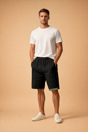 Minimalist white short-sleeve T-shirt paired with black relaxed-fit shorts featuring a subtle green geometric trim at the hem, styled with clean white low-top sneakers for a modern summer casual look