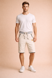 Off-white cotton drawstring shorts with grey ribbed waistband, striped pocket trim, tailored knee-length cut, paired with a clean white short-sleeve crew-neck T-shirt and minimalist white low-top sneakers