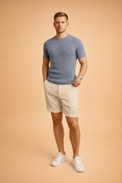 Off-white linen shorts with a lightweight woven texture and clean cuffed hems, paired with a taupe short-sleeve crew-neck T-shirt featuring a fine waffle knit pattern and smooth, matte finish, showcasing a relaxed yet refined summer outfit with natural fabric drape and neutral tones.