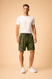 Olive green athletic shorts with elastic waistband and black drawstring, featuring zippered side pockets, subtle black geometric accent lines, paired with a clean white fitted crew neck t-shirt and minimalist white low-profile sneakers for a modern sport-casual look