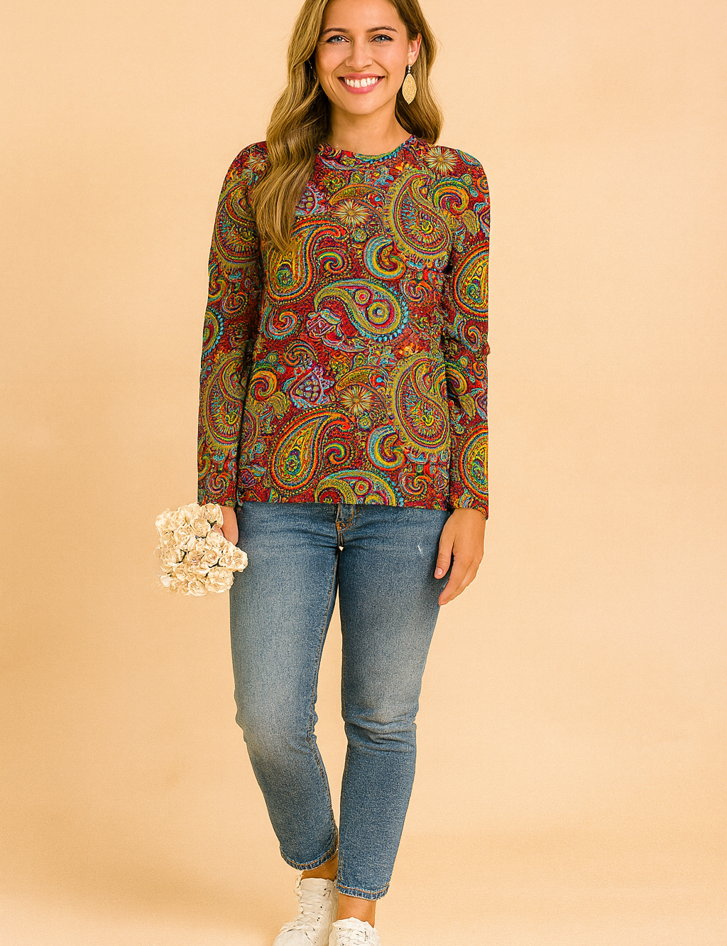 Long-sleeve paisley-print blouse in vibrant red, yellow, blue, and green tones, paired with fitted blue jeans and white sneakers.
