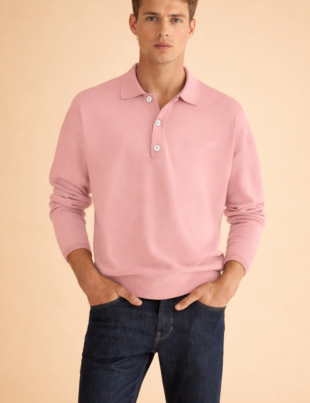 Soft pink long-sleeve polo shirt with classic collar and three-button placket, paired with dark blue straight-leg denim jeans in a clean, tailored fit.