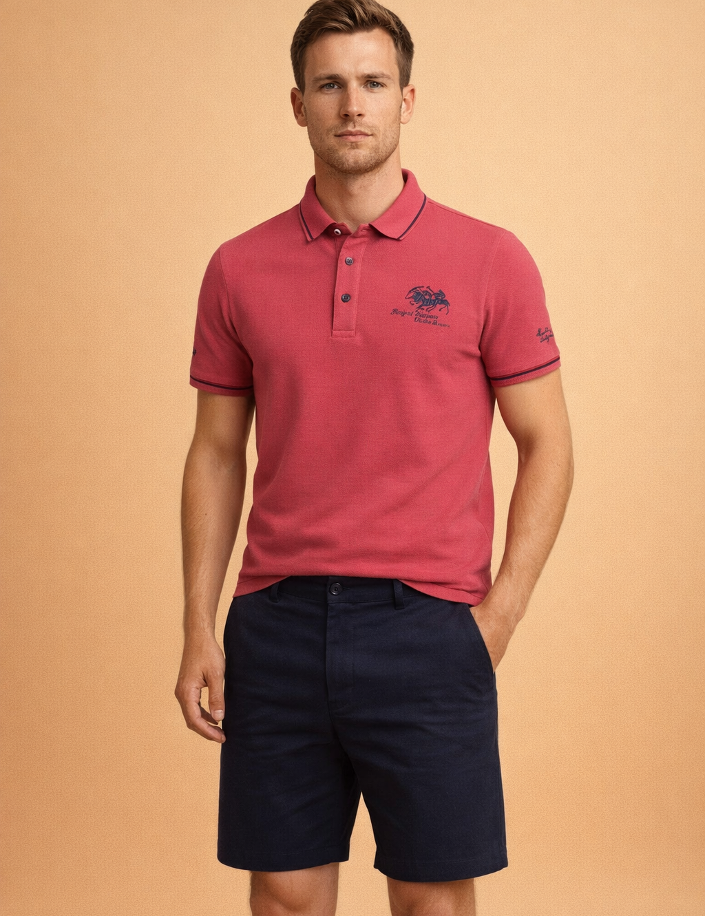 Pink short-sleeve polo shirt with navy contrast collar and sleeve trim, three-button placket, embroidered chest logo, paired with tailored navy shorts