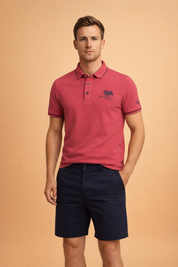 Pink short-sleeve polo shirt with navy contrast collar and sleeve trim, three-button placket, embroidered chest logo, paired with tailored navy shorts